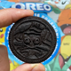 A close up photo of a Mew Pokémon Oreo against a background showing the Pokémon Oreo packaging